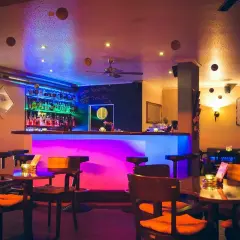 Gemütliche Bar mit bunter Beleuchtung, vielen Flaschen hinterm Tresen und Tischen. Hier kann man im "Liberté Heilbronn" entspannen.