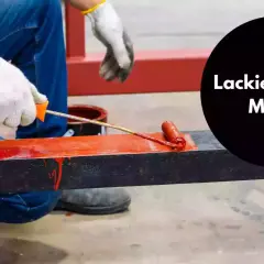 Person lackiert mit einer Farbrolle ein Metallteil rot.