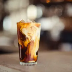Ein Glas Eiskaffee mit Milchwirbeln und Eiswürfeln. Perfekt für ein iced coffee rezept schnell an heißen Tagen.