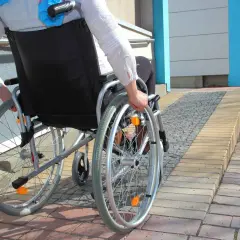 Osoba na wózku inwalidzkim wjeżdża na podjazd, pokazując, jak zrobić podjazd dla niepełnosprawnych.