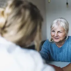 Uśmiechnięta starsza pani rozmawia z opiekunką w domu seniora Anna.