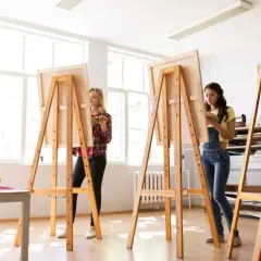 Zwei Frauen malen in einem hellen Atelier. Sie stehen vor Staffeleien, die aussehen, als ob sie jemand selber bauen könnte.