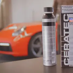 Dwa opakowania LIQUI MOLY CERA TEC obok pomarańczowego samochodu sportowego. Produkt zapewnia optymalną moc i dłuższą żywotność silnika.