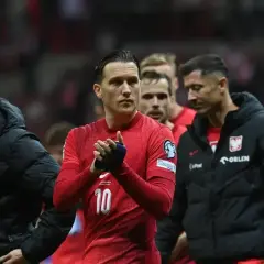 Piłkarze reprezentacji Polski, w tym Lewandowski, w czerwonych strojach i czarnych kurtkach, z nadzieją patrzą w przyszłość, marząc o baraze ms 2026.