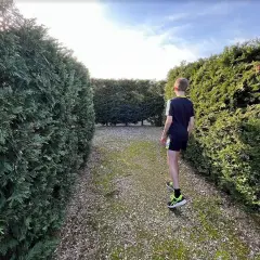 Un niño se adentra en un laberinto de setos verdes, buscando el camino en este laberinto costa mariña.