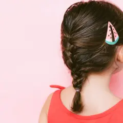 Niña con un bonito peinado de trenza y un pasador de sandía.