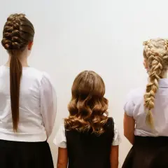 Trzy dziewczynki prezentują fryzury na rozpoczęcie roku szkolnego: warkocz francuski, loki i warkocz dobierany.