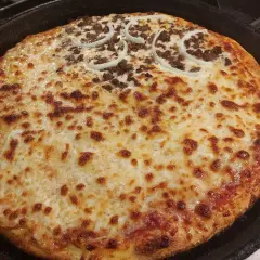 Pyszna pizza supreme z Pizza Hut, z mięsem mielonym i krążkami cebuli, zapieczona na złoto w żeliwnej patelni.