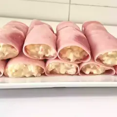 Rollitos de jamón york rellenos de ensaladilla cremosa, presentados en una bandeja blanca.