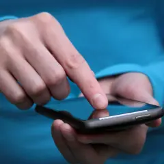 Palec dotyka ekranu smartfona, szukając rozwiązania, jak wyłączyć tryb awaryjny w telefonie.