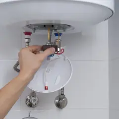 Ręka majstruje przy bojlerze Galmet, przygotowując się do wymiany grzałki.