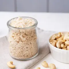 Zutaten für veganen Parmesan selber machen: Cashewkerne in einer Schüssel und fertig gemahlene Masse in einem Glas.