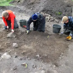 Osoby prowadzą archeologia studia, ostrożnie badając ziemię i kamienie.