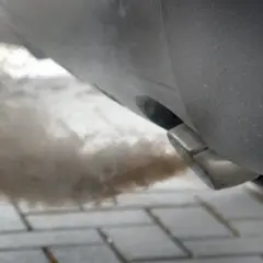 Gęsty dym wydobywa się z rury wydechowej samochodu, co może sugerować problem z DPF. Jak wypalić DPF na postoju, gdy auto kopci?