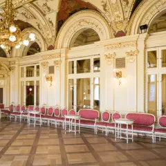 Eleganckie, złocone wnętrze z rzędami czerwonych foteli i stolików. To właśnie co to jest foyer w teatrze – miejsce spotkań przed spektaklem.