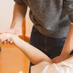 Fizjoterapeuta bada rękę pacjenta z problemem braku czucia w palcach po operacji cieśni nadgarstka.