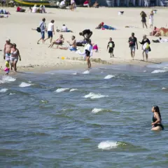 Plaża pełna ludzi, a w wodzie kąpie się kobieta. Warto sprawdzić, ile stopni ma Bałtyk latem, by móc cieszyć się takimi widokami.