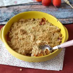 Un délicieux crumble abricot tout juste sorti du four, prêt à être dégusté. La cuillère y a déjà fait un trou.