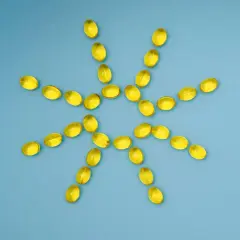 Gelbe Kapseln bilden eine Sonne, die gegen Winterdepression hilft. Vitamin D für mehr Licht.