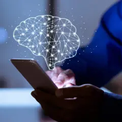 Dłoń trzyma smartfon, nad którym unosi się świetlisty mózg. Aplikacja pomaga zrozumieć, ile czasu się trzeźwieje.