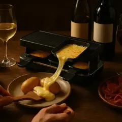 Un délicieux vin rouge accompagne une raclette fondante, des pommes de terre et de la charcuterie.
