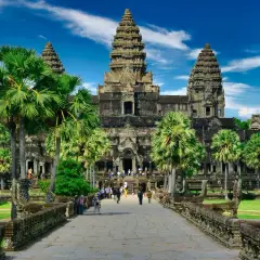 Majestatyczna świątynia Angkor Wat, symbol Kambodży, otoczona palmami pod błękitnym niebem.