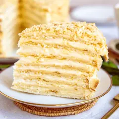 Ein Stück Napoleon Torte mit vielen Schichten Blätterteig und cremiger Füllung, bestreut mit Krümeln.