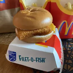 Filet-o-Fish, klasyczny fishburger z McDonald's, na białym pudełku z logo MSC. Obok frytki w czerwonym opakowaniu.