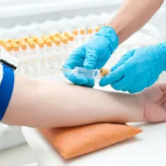 Pobieranie krwi do analizy gazometrycznej. Ręce w niebieskich rękawiczkach pobierają próbkę krwi z żyły.