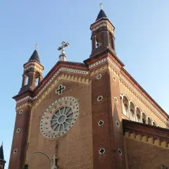 La chiesa San Dalmazzo a Torino, con le sue torri e il rosone, si staglia contro il cielo azzurro.