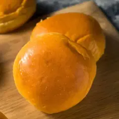 Pains à burger maison dorés et moelleux sur une planche en bois.