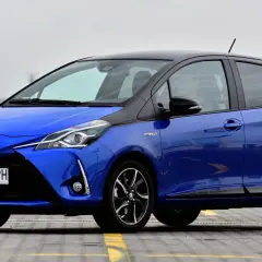 Niebieska Toyota Yaris Hybrid z czarnym dachem, zaparkowana na zewnątrz.