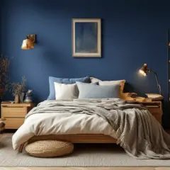 Chambre paisible aux murs bleu profond, un nuancier de bleu qui invite à la détente. Lit douillet, fauteuil confortable et étagères remplies de livres.