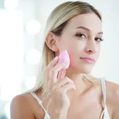 Blondynka z różową gąbeczką delikatnie muska policzek, tworząc naturalny makijaż bez podkładu.