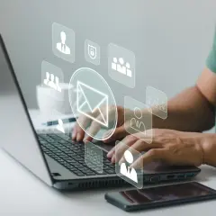 Man typing on laptop, with icons representing communication and security, suggesting a secure correo electrónico certificado.