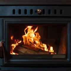 Un feu crépite dans un poêle à bois, le branchement poele a bois est discret derrière la pierre.