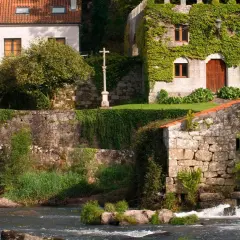 El pazo de Ponte Maceira, con su arquitectura de piedra y vegetación exuberante, se alza junto a un río de aguas bravas.