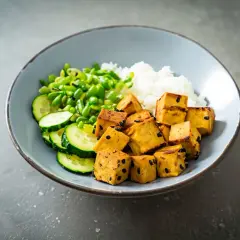Miseczka z ryżem, zielonym groszkiem, ogórkiem i kostkami aromatycznego, wędzonego tofu.