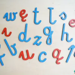 Drewniane litery alfabetu łacińskiego w kolorach niebieskim i czerwonym, ułożone na drewnianym tle.