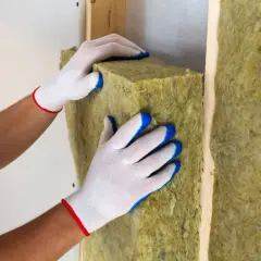 Mani guantate posizionano un pannello isolante per creare un solaio termico efficiente.