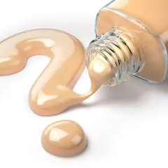Kremowy fluid wylewa się z buteleczki, tworząc na białym tle kształt znaku zapytania.