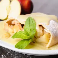 Ein köstlicher Apfelstrudel, übergossen mit Vanillesauce und garniert mit Minze. Perfekt für ein Apfelstrudel Rezept.