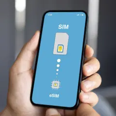 Dłoń trzyma smartfon z ekranem pokazującym przejście od tradycyjnej karty SIM do eSIM. Idealne rozwiązanie na kartę SIM internet za granicą.