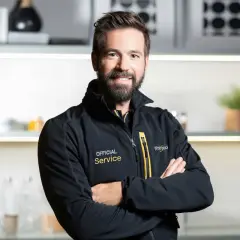 Uśmiechnięty serwisant Whirlpool w czarnej kurtce z napisem "Official Service". Pomoże Ci z instrukcją obsługi pralki Whirlpool.