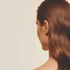 Cabello castaño brillante con un volumen envidiable, cayendo en ondas suaves sobre el hombro.