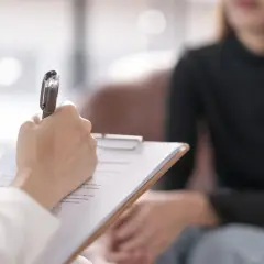 Psycholog prowadzi diagnozę różnicową, notując spostrzeżenia podczas rozmowy z pacjentem.