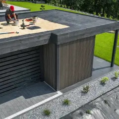 Handwerker arbeitet an der Dachhaut eines modernen Flachdachs. Materialien und Werkzeuge liegen bereit für die Abdichtung.