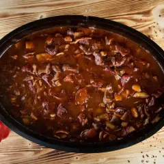 Herzhaftes Gulasch im Dutch Oven, perfekt für rustikale Dutch Oven Rezepte. Daneben liegt eine rote Paprika.