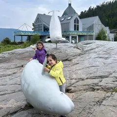 Due bambine giocano con sculture di balene a Canada orientale, vicino a un centro di interpretazione.