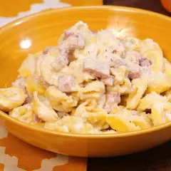 Tortellini panna e prosciutto, un piatto cremoso e saporito, servito in una ciotola gialla.